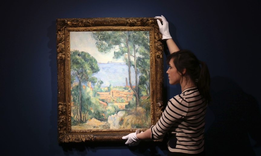 A Christie's staff member poses for a photograph next to "Vue sur L'Estaque et Le Chateau d'If" by Paul Cezanne in London
